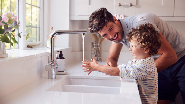 Boy and father washing hands