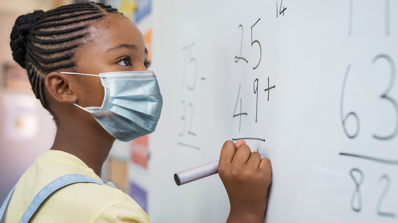 Black girl face mask writing math problem