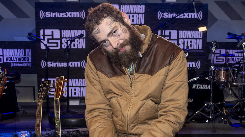 Post Malone sitting with his head cocked on "The Howard Stern Show" set