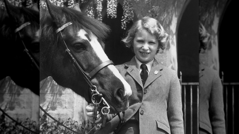 Young Princess Anne posing with a horse 