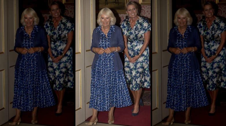 Queen Camilla and woman walking through door smiling