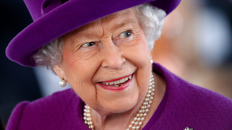 Queen Elizabeth smiling and wearing pearls