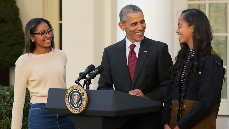 Sasha and Malia Obama smiling at Barack Obama, who is smiling back