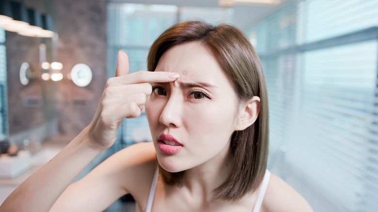 Woman checking her skin in the mirror