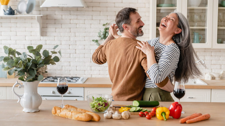 Middle-aged couple dancing and laughing in kitchen