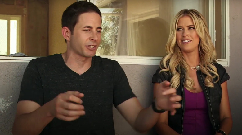 Tarek El Moussa sitting next to Christina Haack with his arms up