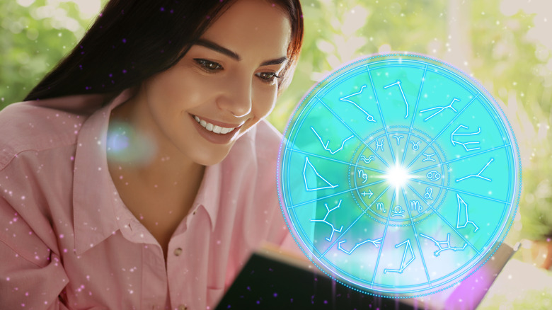 A woman reading a book near a zodiac wheel. 