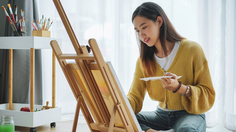 A woman painting on a canvas. 