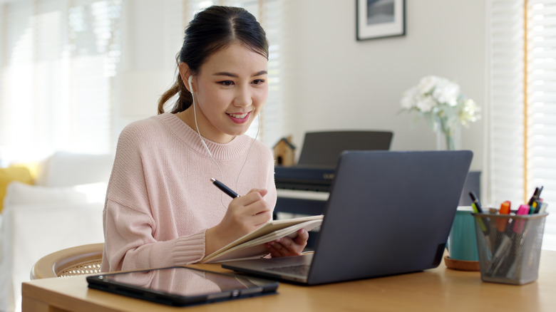 Woman taking notes work call 