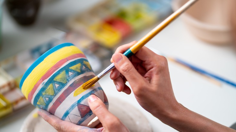 someone painting a pot with a brush 