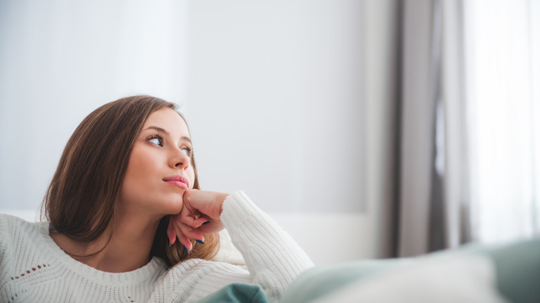 Woman deep in thought on sofa at home 