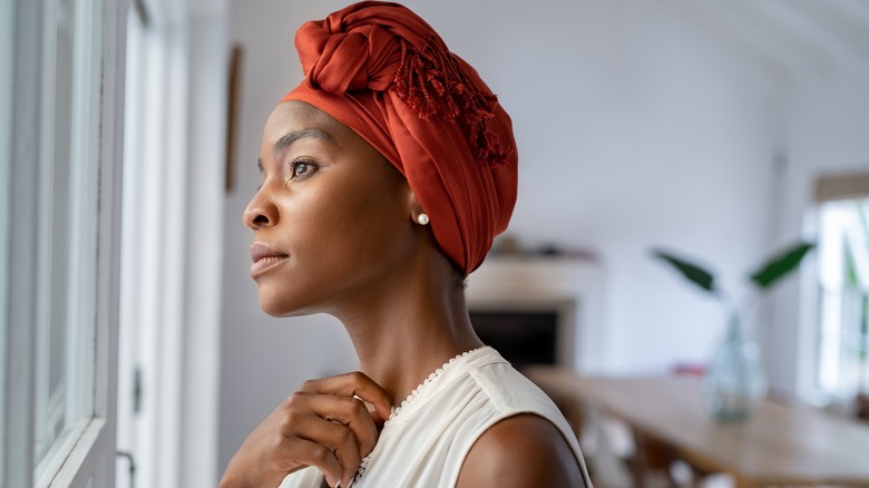 A woman looking pensive while looking out her window. 