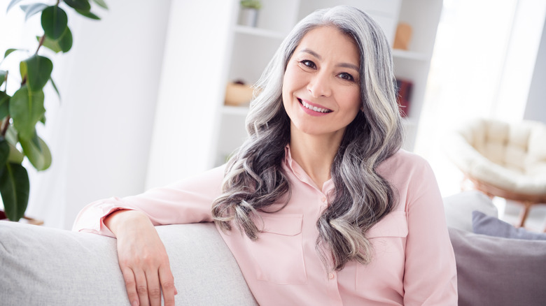 A woman smiles while sitting on a couch