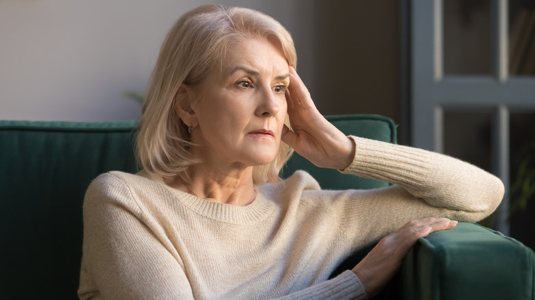 A woman looking pensive at her home. 