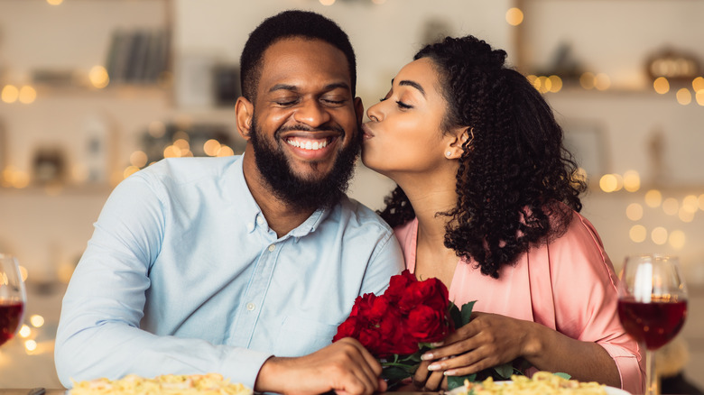 A woman kissing a man on the cheek. 