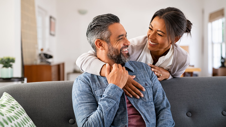 A woman hugging a man on a couch. 