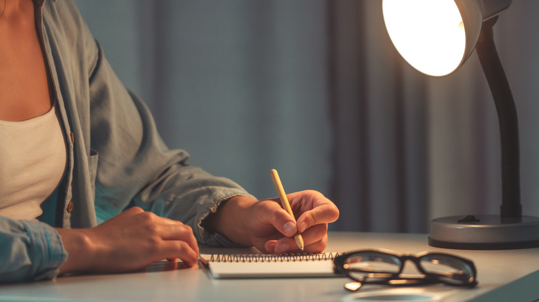 Scorpio woman writing in her journal at her desk for the new moon