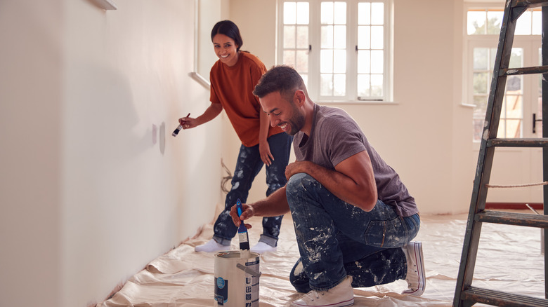 A couple painting a room. 