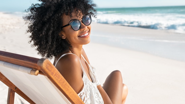 woman sitting in a chair at the beach smiling