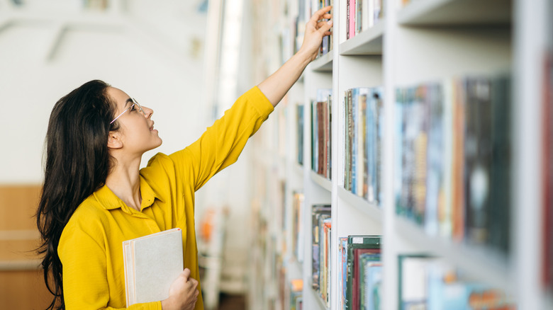 Woman reaching for a book on a shelf