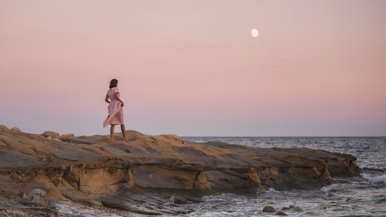 Woman walking on the beach by a full moon