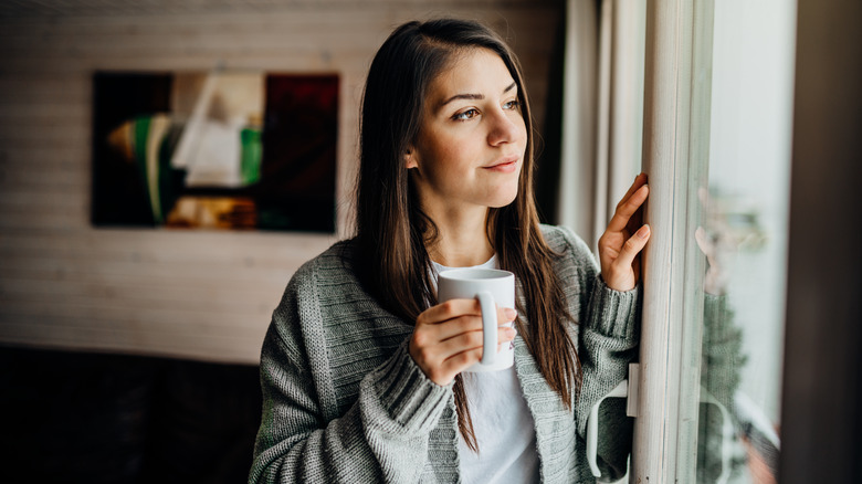 A woman enjoying a drink from a mug. 