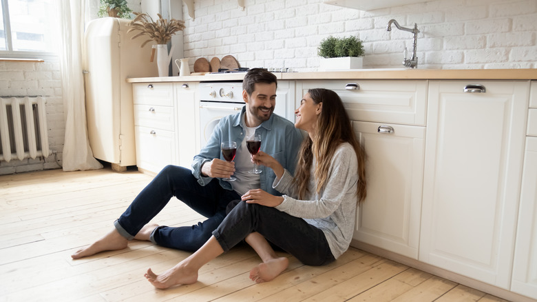 Couple drinking a glass of wine on the kitchen floor