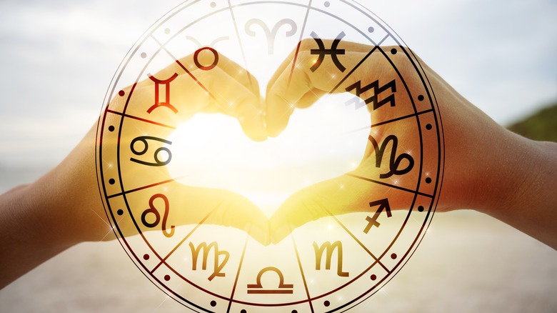 Two hands making a heart behind the zodiac wheel 