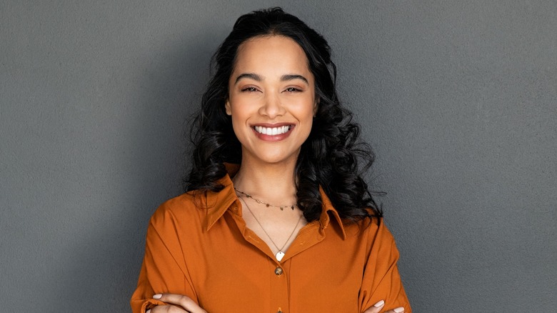 A woman smiles with her arms crossed. 