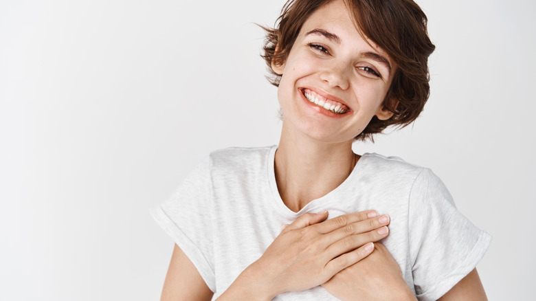 A woman smiling with her hands over her heart.