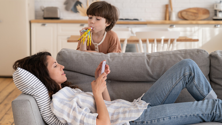 parent looks at phone on couch 