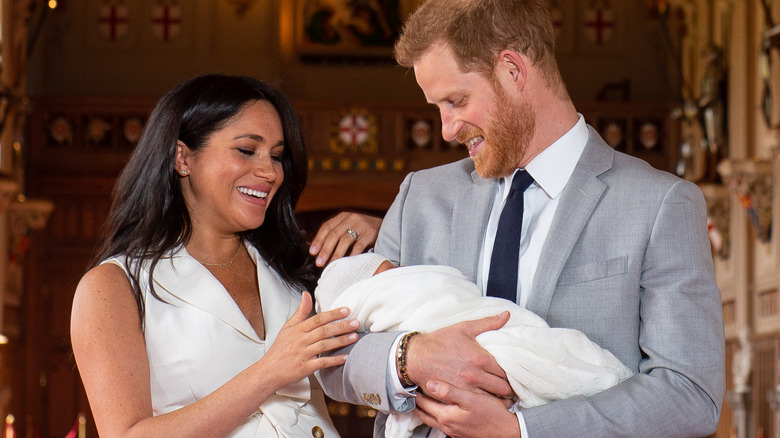 Meghan Markle smiling while Prince Harry holds newborn Archie