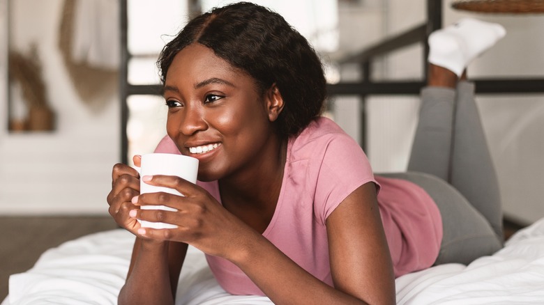 A woman enjoying coffee in bed. 