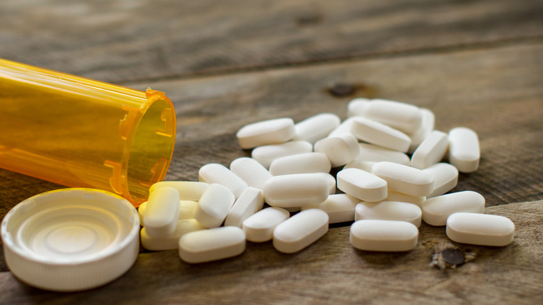 pills on a wooden surface with an empty pill bottle tipped over