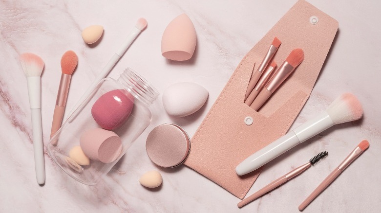 Makeup tools, including brushes and beauty sponges, on a marble table