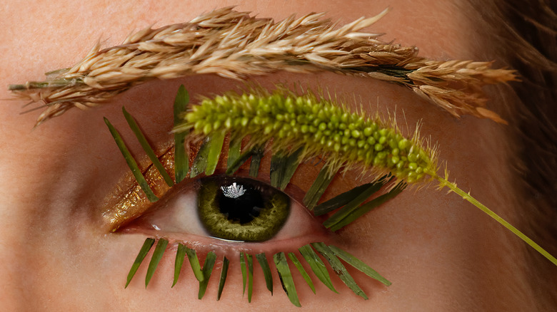 Woman with blades of grass as lashes and gold eyeshadow