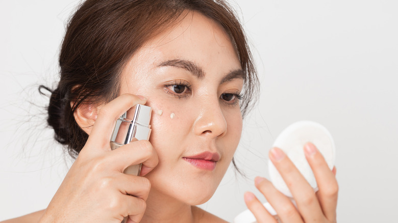 A woman using liquid foundation on her face