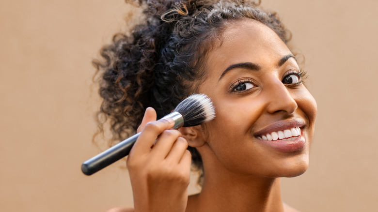 A woman putting makeup on with a brush