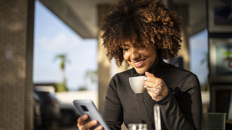 woman with phone drinking coffee