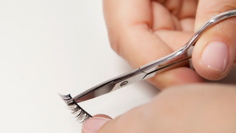 Person trimming a false eyelash