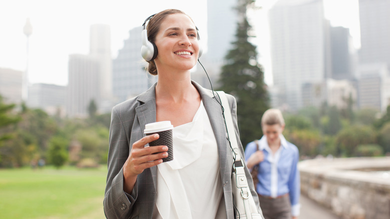 A woman walking while holding her coffee. 