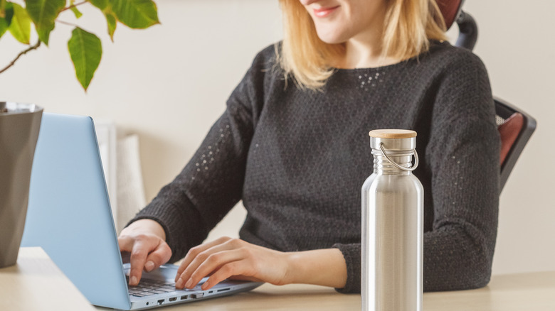 A woman with a water bottle on her desk. 