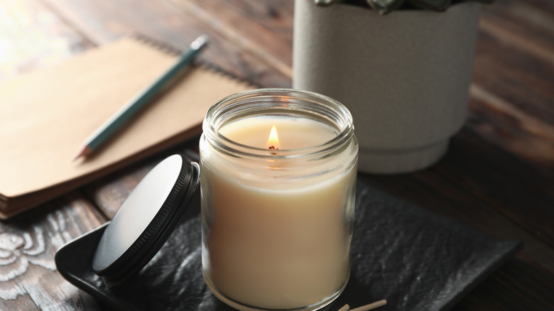 A candle burning in a glass jar. 