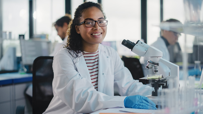 Young women smiling while using a microscope in a lab