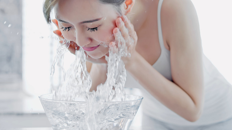 woman washing her face in a step by step skincare routine