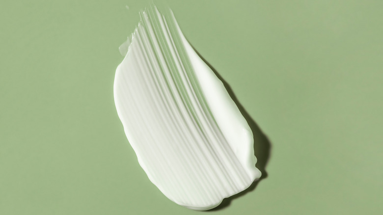 Cream skincare product on a green background