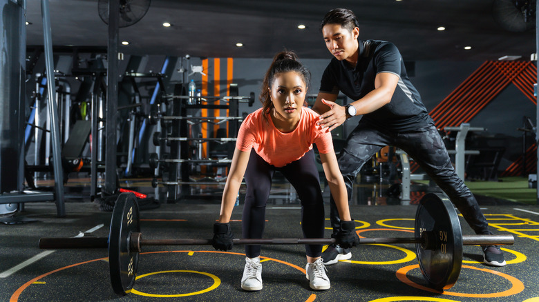 Personal trainer showing his client how to deadlift