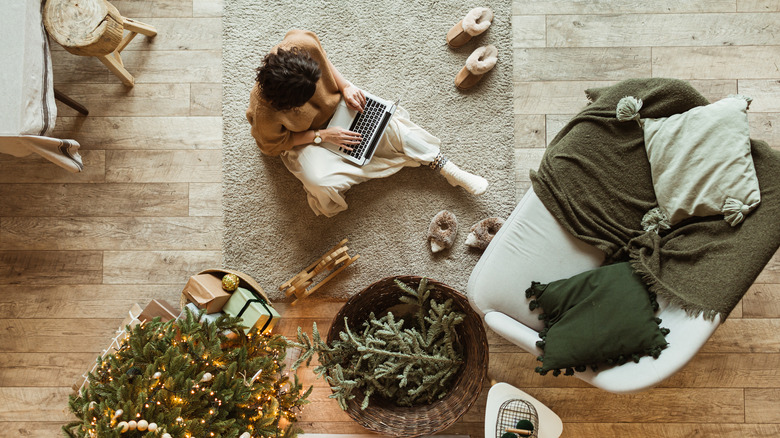 Woman on laptop by Christmas tree