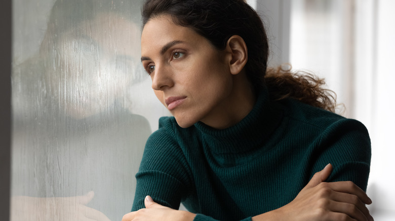 Pensive woman lean against window