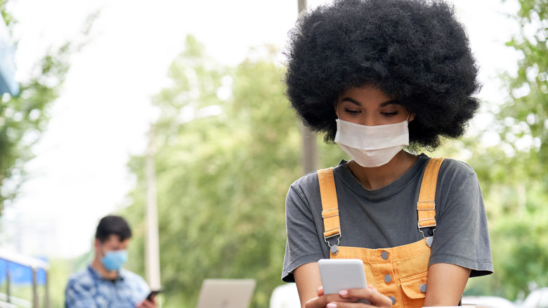 Woman alone at outdoor café wearing face mask